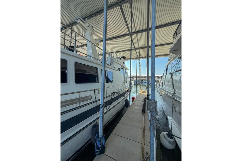 Slide: The Image of 2007 Nordic Tug 54 cruising on a serene lake under a clear blue sky. - 5