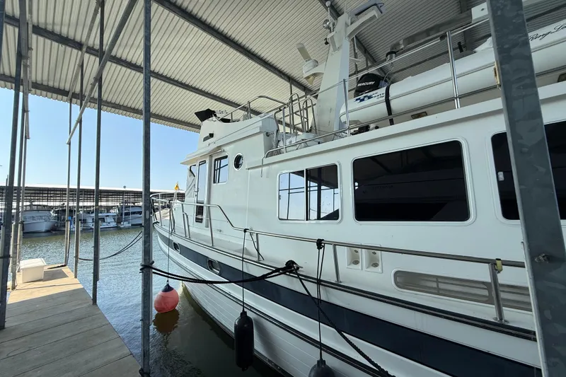 Slide: The Image of 2007 Nordic Tug 54 yacht cruising on a calm lake under a clear blue sky. - 7