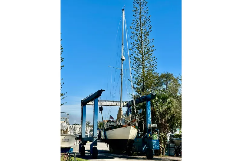 Slide: The Image of 1979 Westsail 32 Shipmaster sailboat on a lift, surrounded by trees and clear blue sky. - 2
