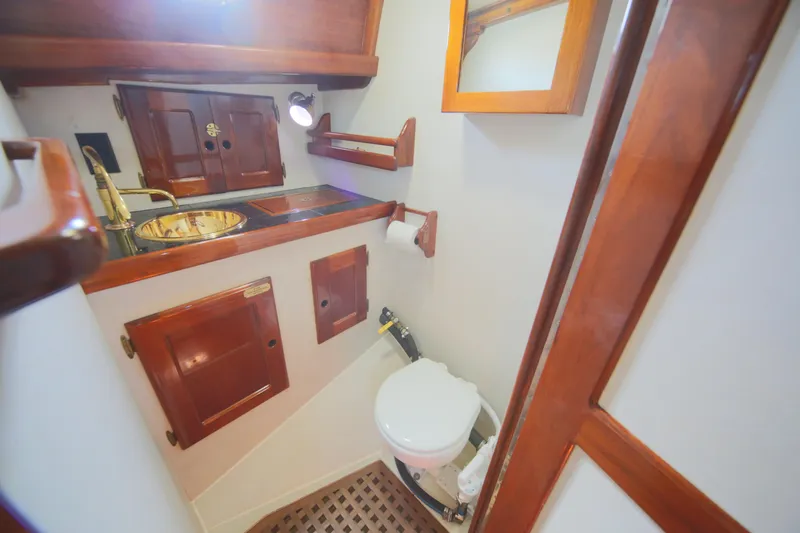 Slide: The Image of 1979 Westsail 32 Shipmaster bathroom with wooden cabinetry and brass sink. - 34
