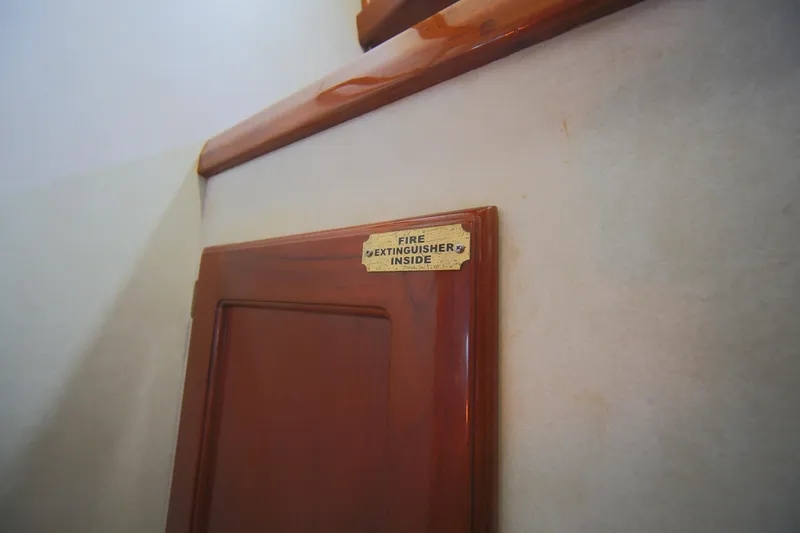 Slide: The Image of Wooden panel with "Fire Extinguisher Inside" sign on 1979 Westsail 32 Shipmaster. - 40