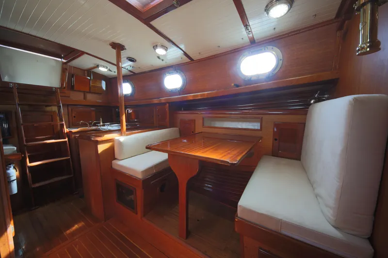 Slide: The Image of Interior of 1979 Westsail 32 Shipmaster, featuring wooden dining area and porthole windows. - 41