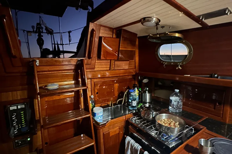 Slide: The Image of Interior of 1979 Westsail 32 Shipmaster with wooden cabinetry and cooking area at sunset. - 71