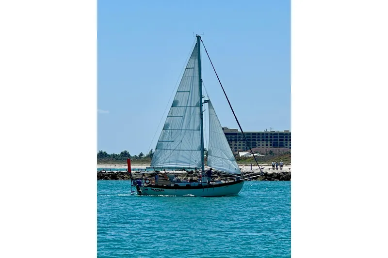 Slide: The Image of Sailing yacht Westsail 32 Shipmaster 1979 on clear blue water near a beach. - 72