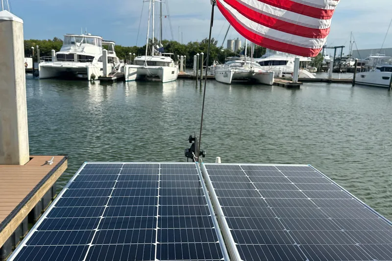 Slide: The Image of Solar panels on a 1979 Westsail 32 Shipmaster, docked with boats in the background. - 82