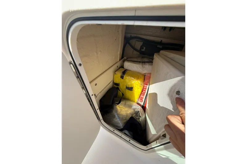 Slide: The Image of Storage compartment in 2019 Robalo R227 Dual Console with life jackets and gear. - 12