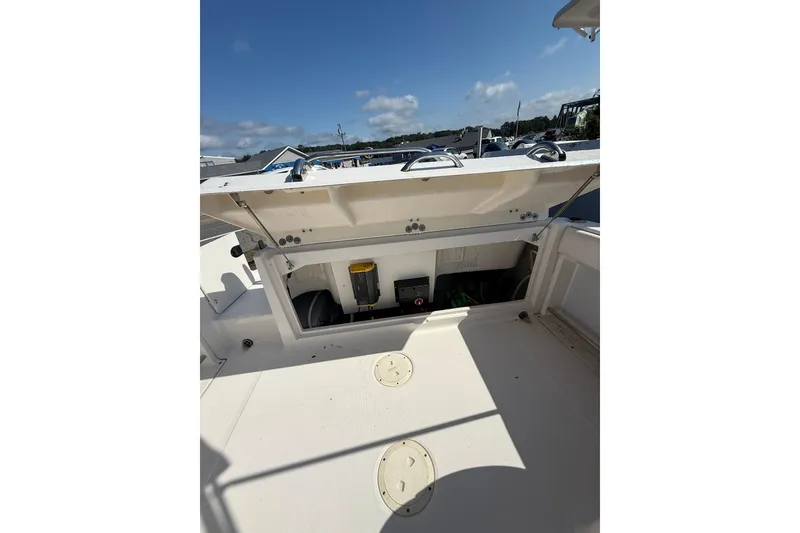 Slide: The Image of 2019 Robalo R227 Dual Console boat storage compartment open under clear sky. - 15