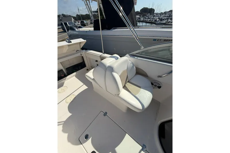 Slide: The Image of 2019 Robalo R227 Dual Console boat interior with white seating and marina background. - 9