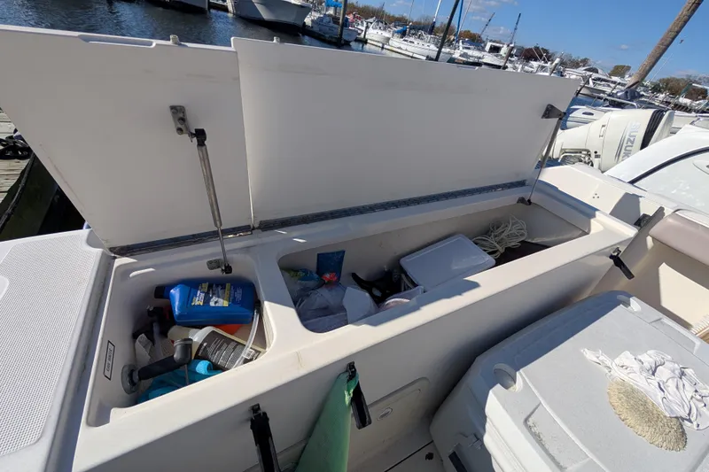 Slide: The Image of Open storage compartment on a 2004 Pursuit 2870 Center Console boat, docked at a marina. - 9