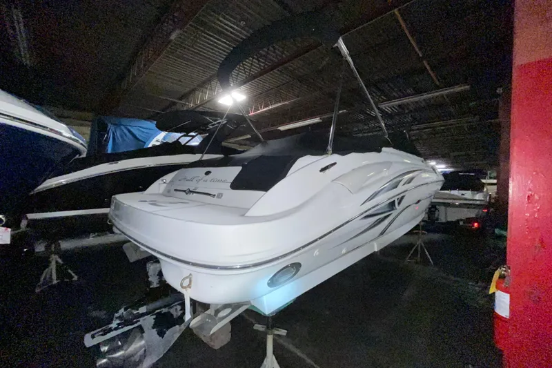 Slide: The Image of 2002 Sea Ray 270 Sundeck boat in storage, rear view, under dim lighting. - 3