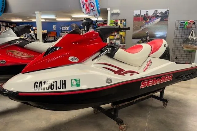 Slide: The Image of 2006 Sea-Doo Wake jet ski in showroom, red and white design, side view. - 2