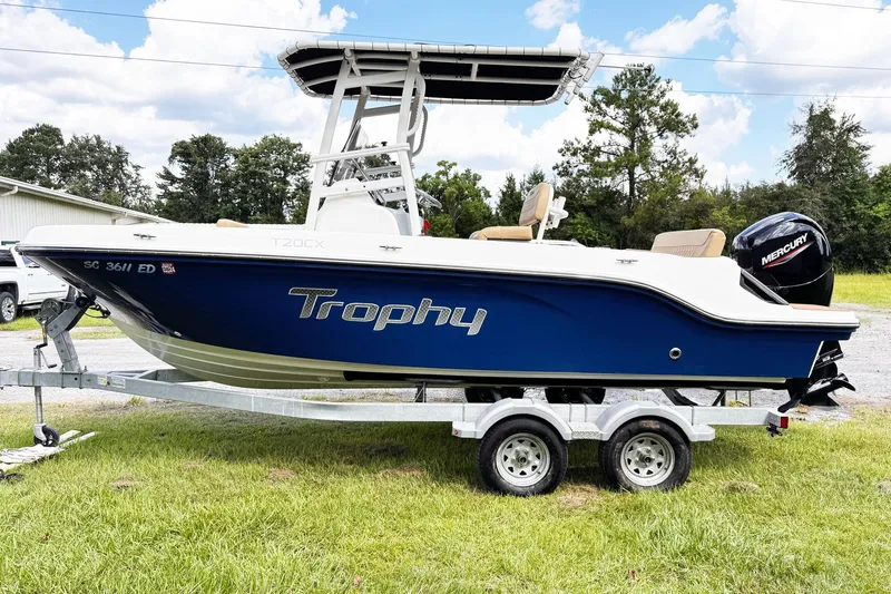 Slide: The Image of 2023 Bayliner Trophy T20CC boat on trailer, blue hull, Mercury engine, outdoor setting. - 3