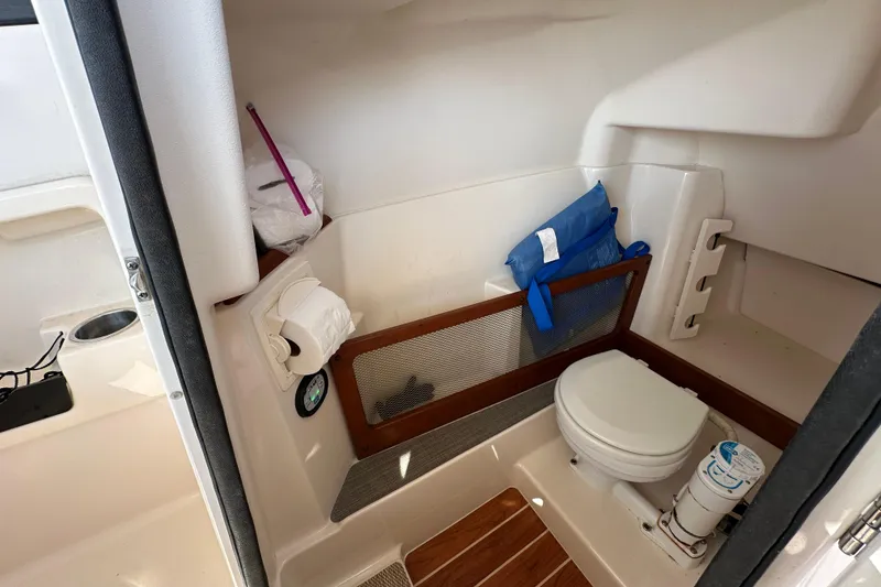 Slide: The Image of 2016 Grady-White Freedom 275 boat interior with seating and windshield, parked near a road. - 81