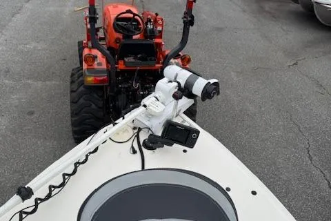 Slide: The Image of 2002 Seafox 195 Bay Fisher boat with mounted equipment, parked near a red tractor. - 6