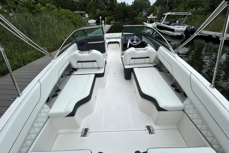 Slide: The Image of 2022 Regal LX4 boat interior with white seating, docked by lush greenery. - 4