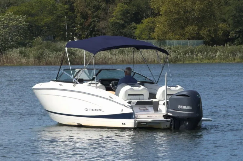 Slide: The Image of 2023 Regal LX4 boat with Yamaha engine on a serene lake. - 2