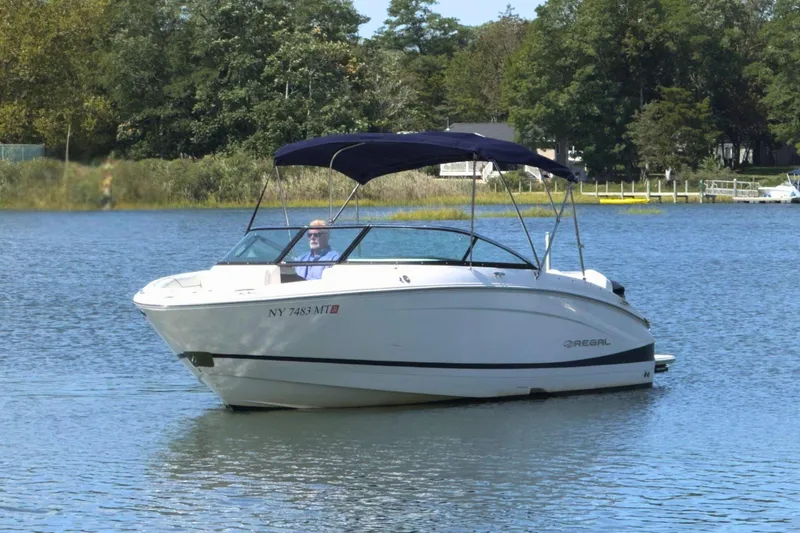 Slide: The Image of 2023 Regal LX4 boat on a serene lake with lush greenery. - 3