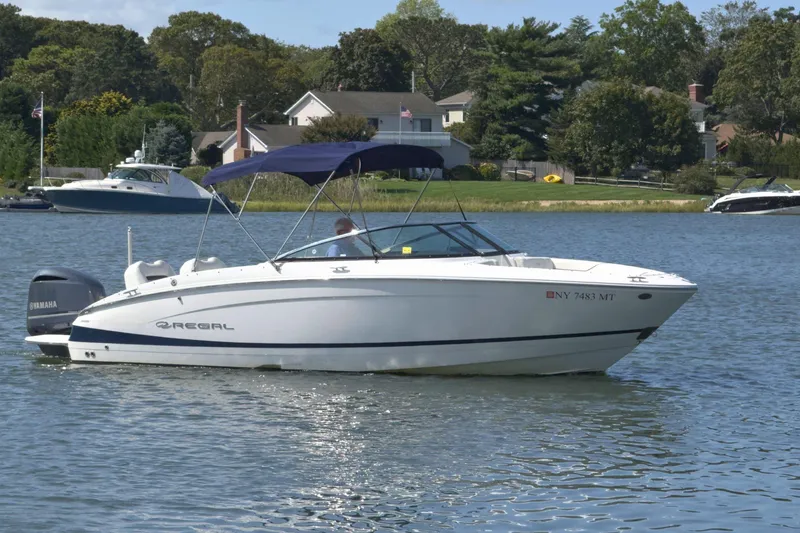 Slide: The Image of 2023 Regal LX4 boat on a calm lake with scenic background. - 4