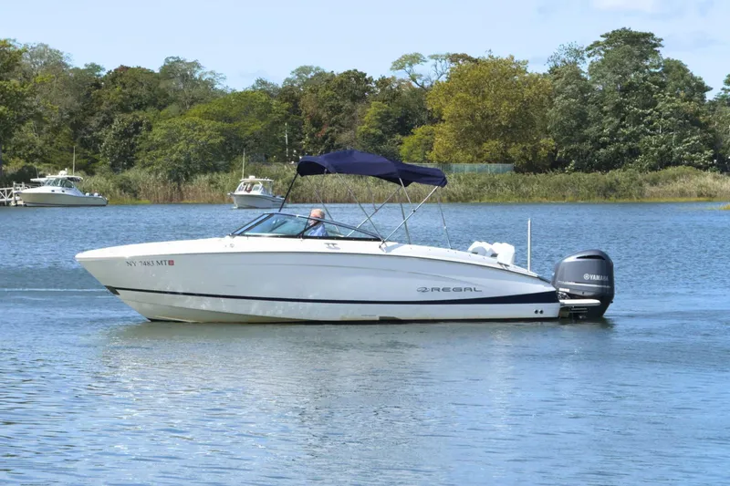 Slide: The Image of 2023 Regal LX4 boat cruising on a serene lake with lush greenery. - 5