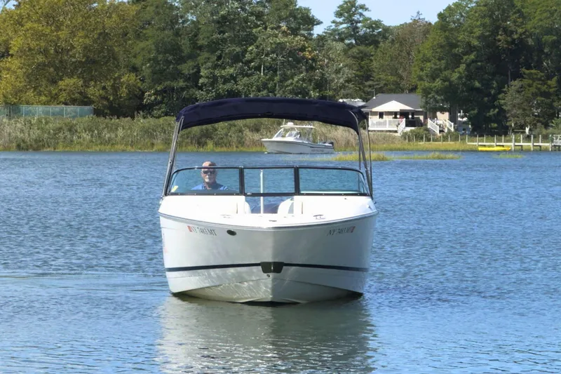 Slide: The Image of 2023 Regal LX4 boat cruising on a serene lake with lush greenery in the background. - 6