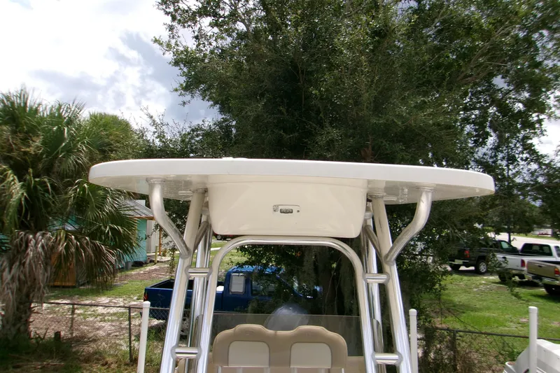 Slide: The Image of 2020 Key West 219 FS boat with T-top, parked outdoors near trees. - 10