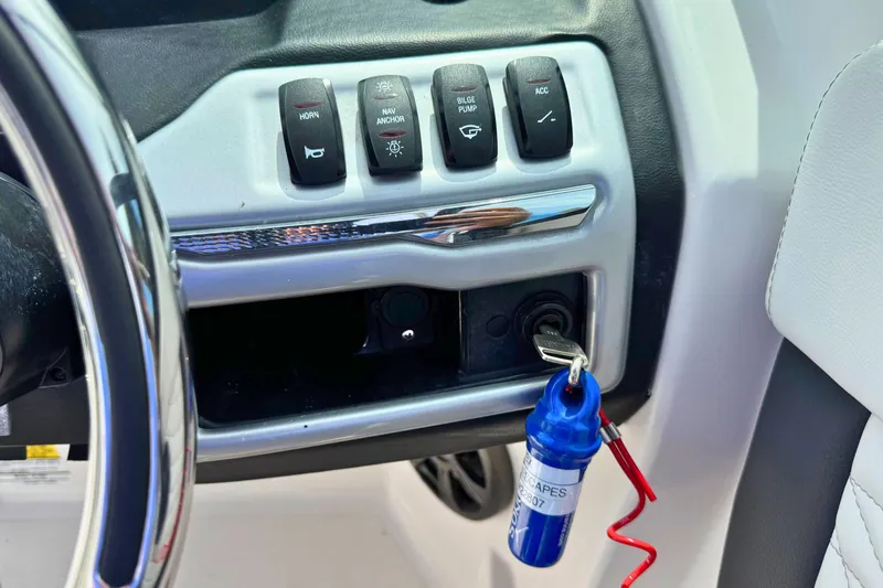Slide: The Image of 2022 Regal 23 OBX boat dashboard with control switches and ignition key. - 17