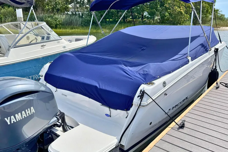 Slide: The Image of 2022 Regal 23 OBX boat with blue cover docked beside Yamaha engine. - 23