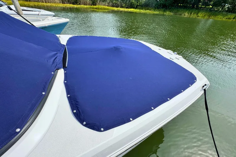 Slide: The Image of 2022 Regal 23 OBX boat with blue cover on calm water. - 24
