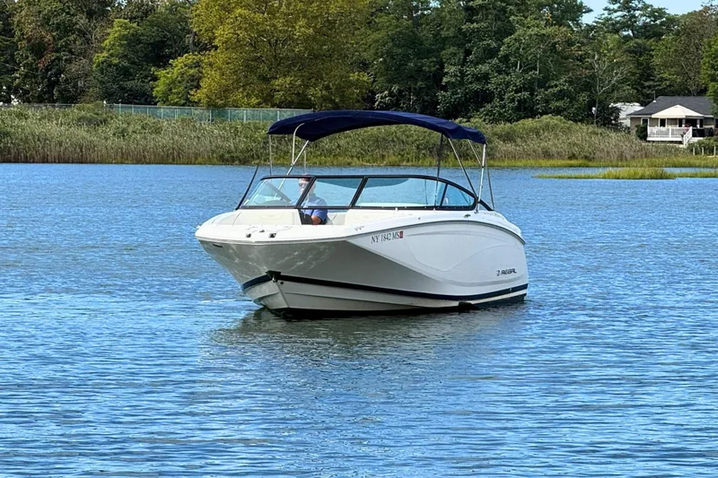 Slide: The Image of 2022 Regal 23 OBX boat on a serene lake with lush greenery. - 3
