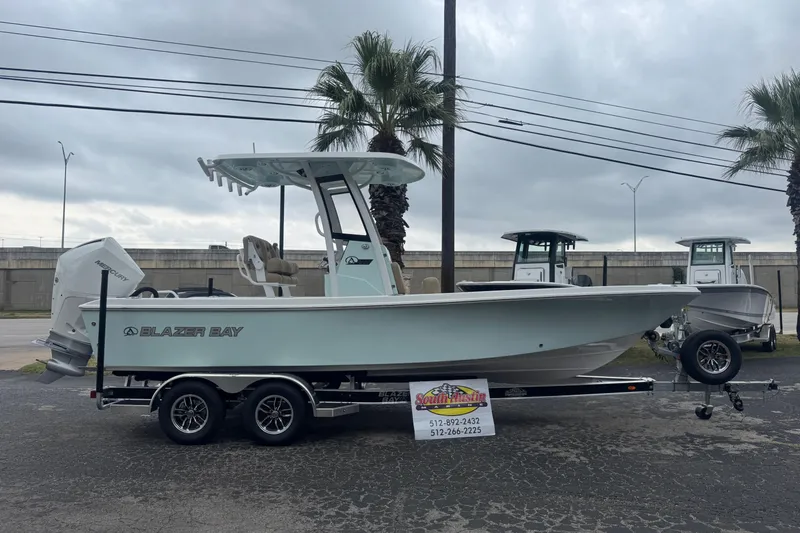 The Image of 2026 Blazer Bay 2440 boat on trailer, parked outdoors with palm trees in background. - 1
