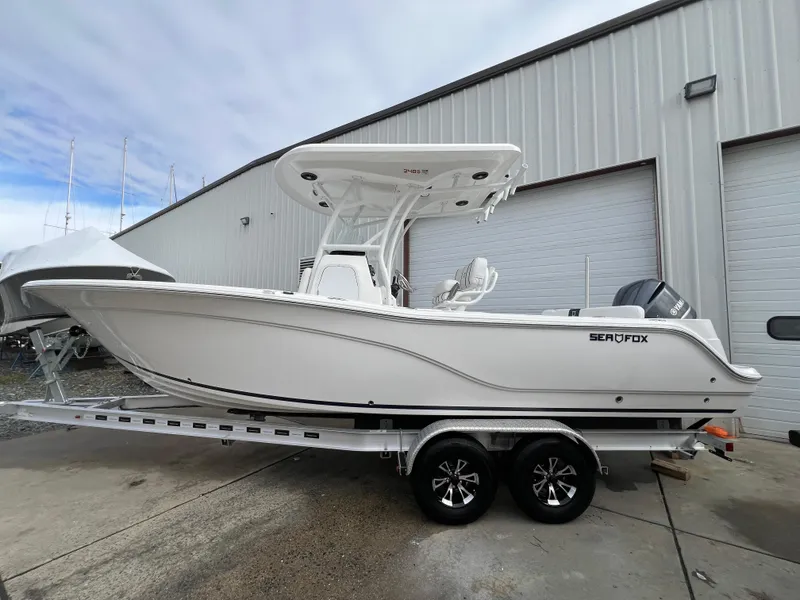 Slide: The Image of 2024 Sea Fox 248 Side Console boat on trailer, parked outside a warehouse. - 3