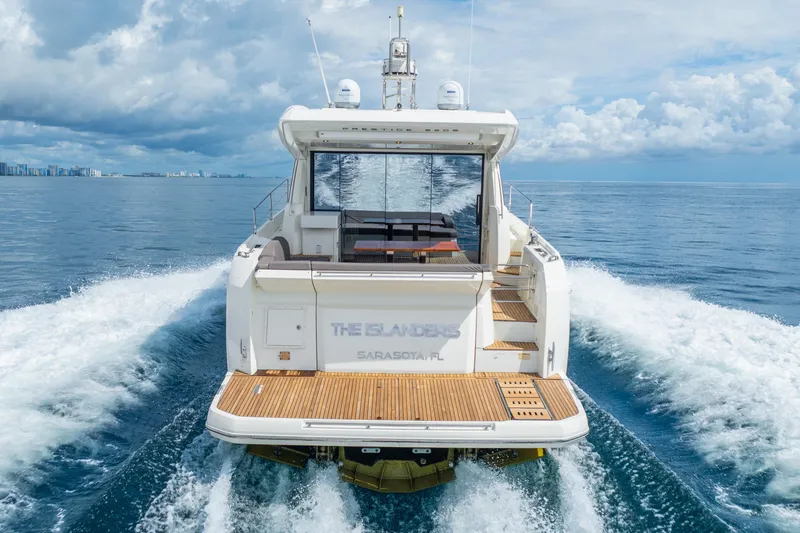 Slide: The Image of 2018 Prestige 520S yacht cruising on open water, rear view, with city skyline in background. - 21