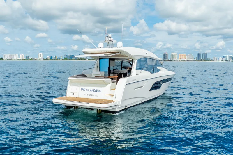 Slide: The Image of 2018 Prestige 520S yacht cruising near a city skyline under a cloudy sky. - 7