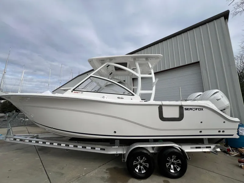 Slide: The Image of 2024 Sea Fox 268 Traveler boat on trailer, parked outside a large garage. - 4