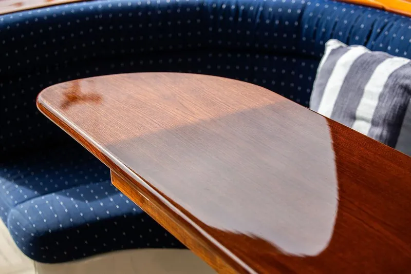 Slide: The Image of Polished wooden table on 2005 Hinckley Talaria 40 yacht with blue cushioned seating. - 12