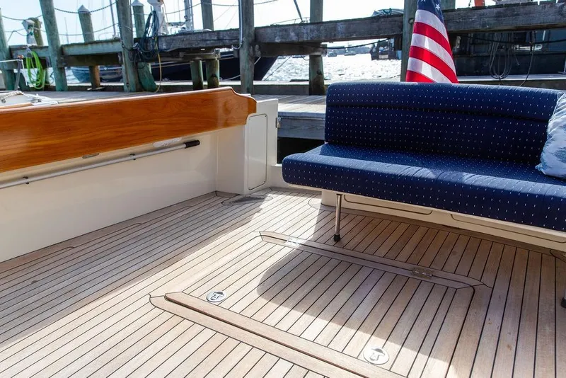 Slide: The Image of 2005 Hinckley Talaria 40 yacht deck with wooden flooring and blue cushioned seating. - 24