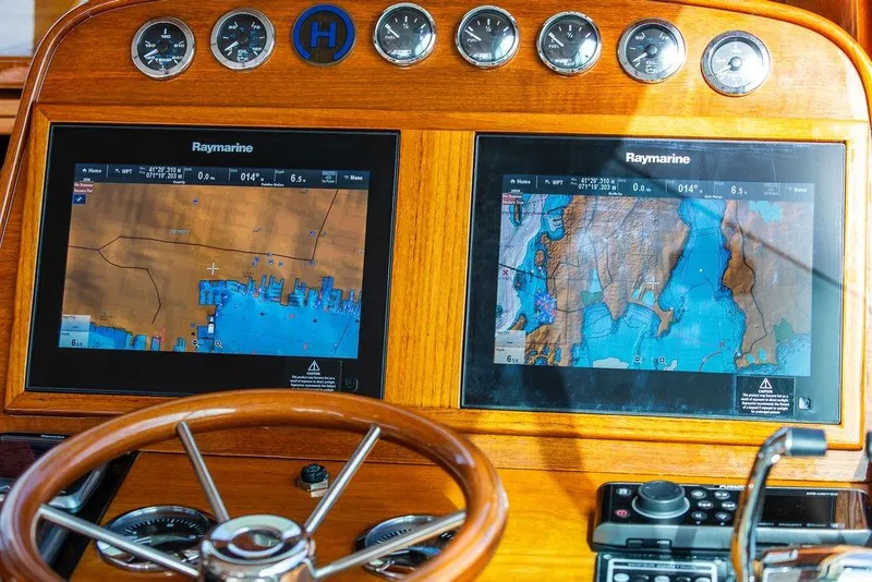 Slide: The Image of 2005 Hinckley Talaria 40 dashboard with Raymarine navigation displays and wooden steering wheel. - 14