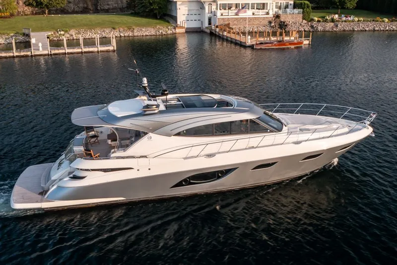 The Image of 2022 Riviera 6000 Sport Yacht Platinum cruising on a serene waterway. - 0