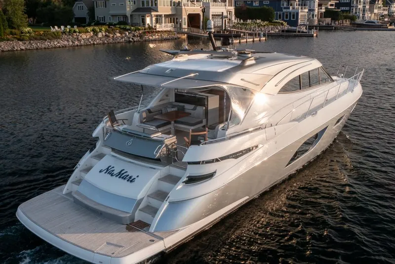 Slide: The Image of 2022 Riviera 6000 Sport Yacht Platinum cruising near waterfront homes. - 1