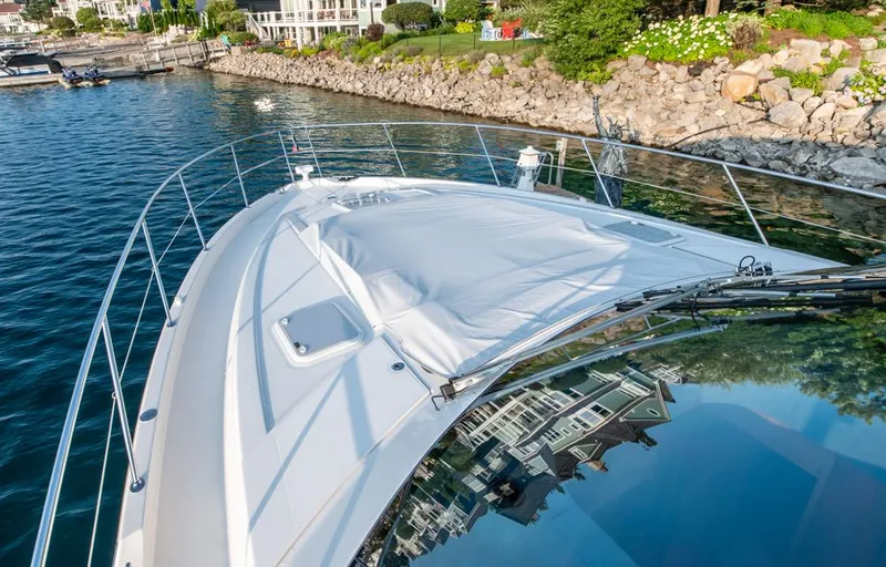 Slide: The Image of 2022 Riviera 6000 Sport Yacht Platinum docked by rocky shoreline. - 10