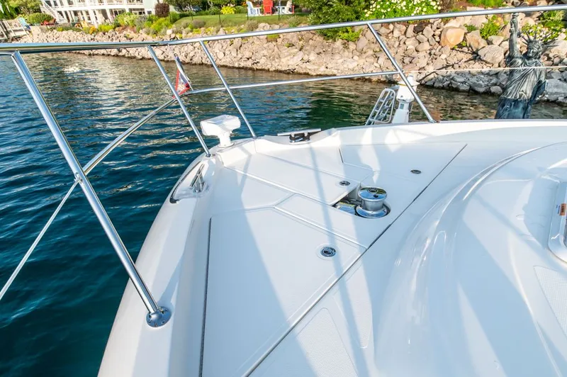 Slide: The Image of Riviera 6000 Sport Yacht Platinum 2022 on water near rocky shoreline. - 11