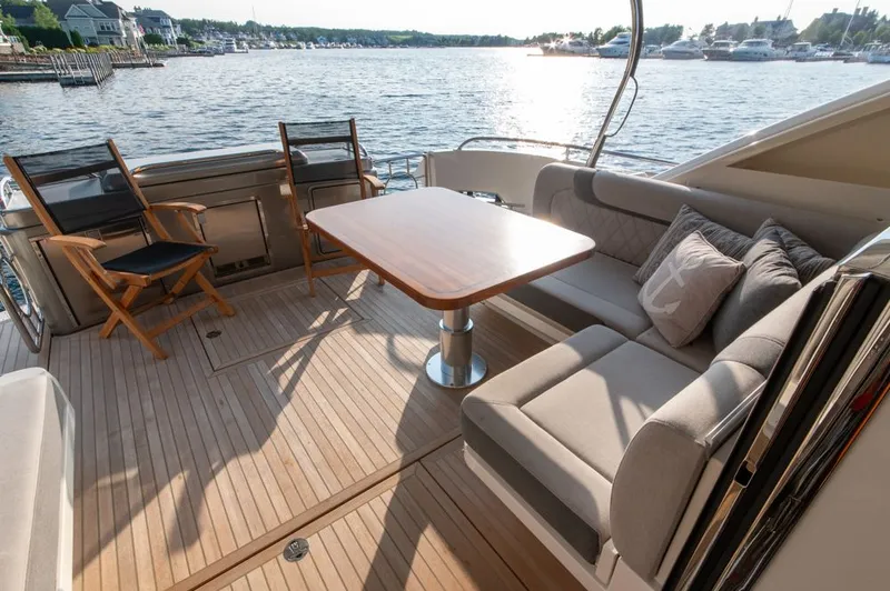 Slide: The Image of Luxurious 2022 Riviera 6000 Sport Yacht Platinum deck with seating and table, overlooking serene waters. - 14