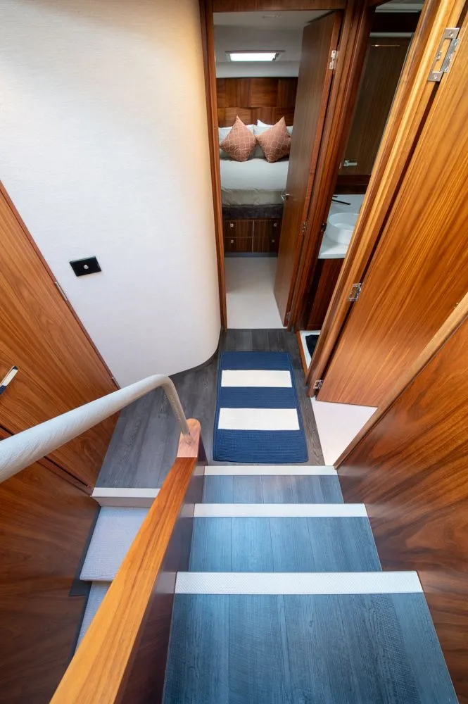 Slide: The Image of Interior of 2022 Riviera 6000 Sport Yacht Platinum, featuring wooden stairs and cozy bedroom. - 42