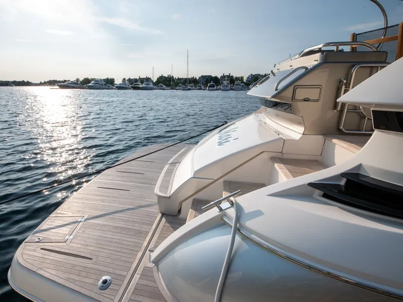 Slide: The Image of 2022 Riviera 6000 Sport Yacht Platinum on serene water at sunset. - 8