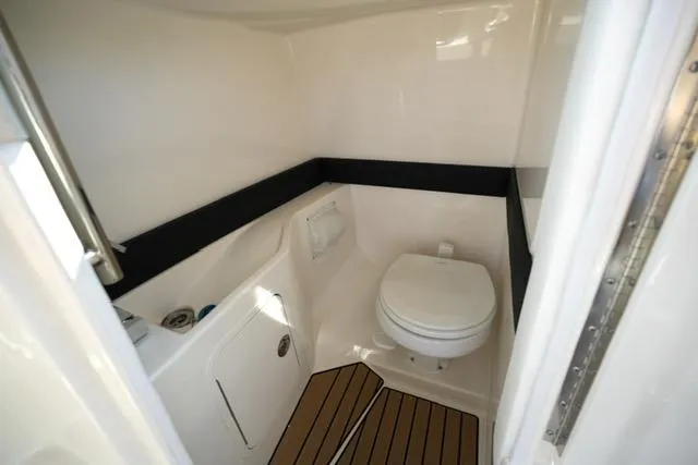 Slide: The Image of 2024 Sea Ray 280 SLX boat bathroom interior with toilet and wooden flooring. - 13