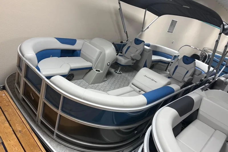 The Image of 2025 South Bay 222 LE pontoon boat with blue and white seating, under a canopy. - 0