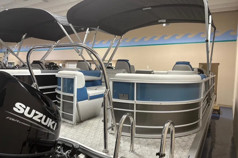 Slide: The Image of 2025 South Bay 222 LE pontoon boat with Suzuki engine in showroom. - 2