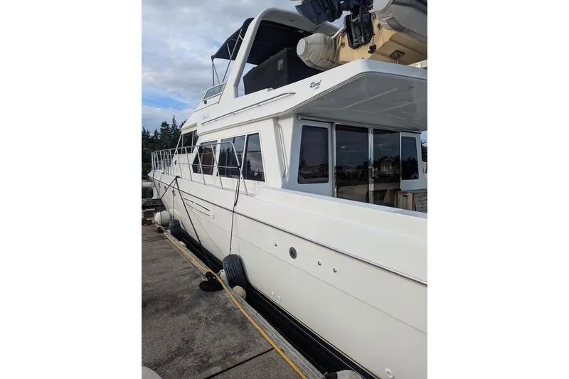 Slide: The Image of 2004 Navigator 57 yacht docked, showcasing sleek design and spacious upper deck. - 2