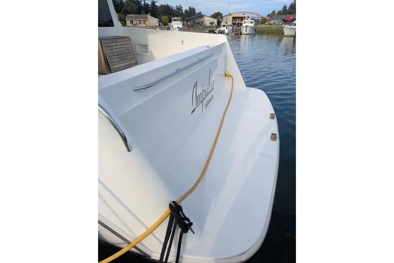 Slide: The Image of 2004 Navigator 57 yacht docked, featuring "Impulse" name on the stern, with water and houses in background. - 21