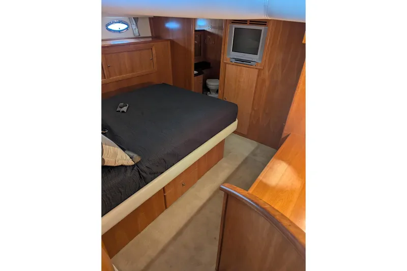 Slide: The Image of 2004 Navigator 57 yacht bedroom with wood paneling, bed, TV, and porthole window. - 9